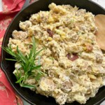 smoked potato salad in a cast iron skillet ready to go into a Traeger pellet grill.