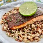 Jerk Salmon recipe on a bed of rice medley with a lime slice on top.