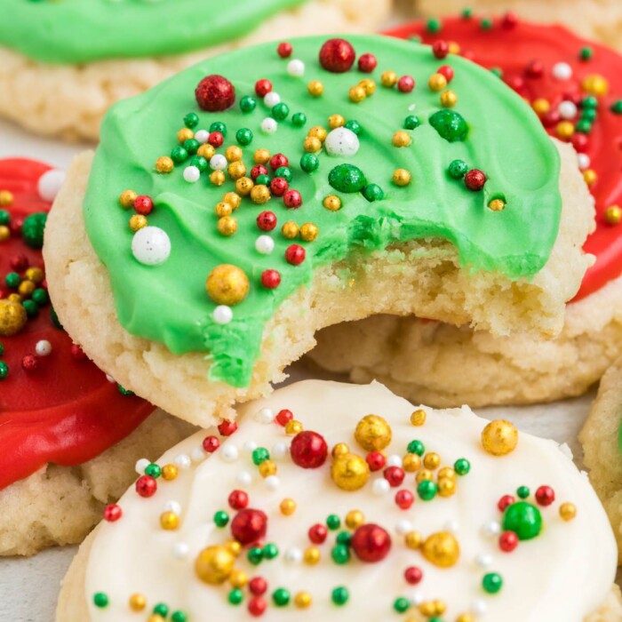 Christmas sprinkle sugar cookies with a bite taken out of one.