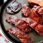 Smoked baby back ribs with bbq sauce on a black cast iron plate.