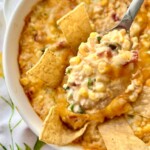 Spoon of cream cheese corn dip in a white bowl.