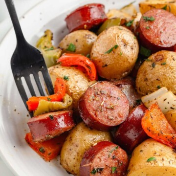 Fork biting into sausage and peppers.