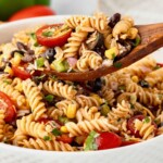 Taco pasta salad being served with a wooden spoon.