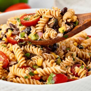 Taco pasta salad being served with a wooden spoon.