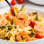 Shrimp pasta with vegetables on a fork.