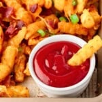 Loaded fries dipped in ketchup.