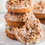 Pumpkin spice donuts on a stack of white plates.