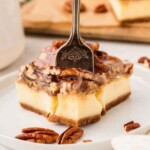 Fork piercing pecan pie cheesecake bars.