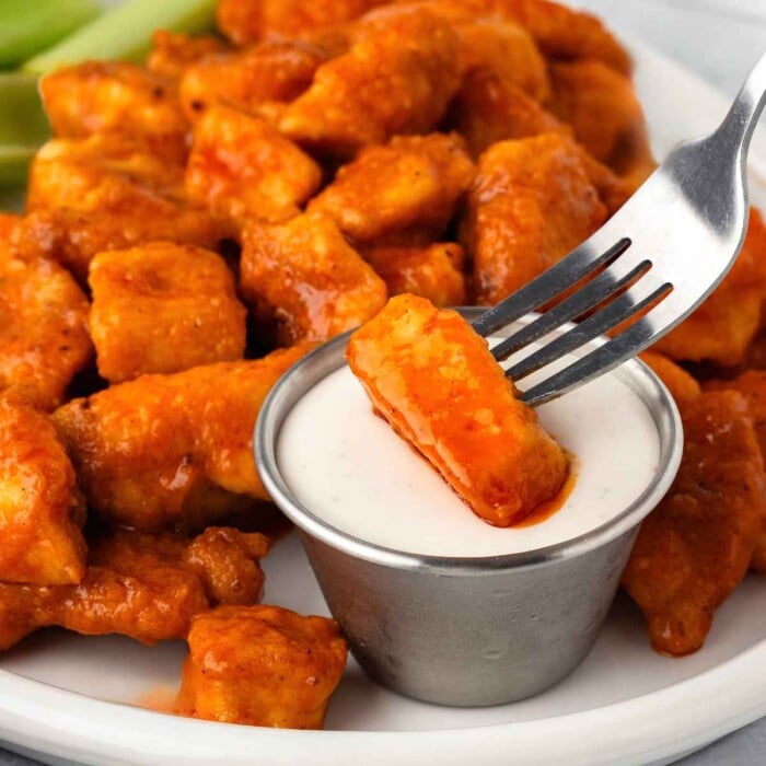 Buffalo chicken bites being dunked into ranch dip.