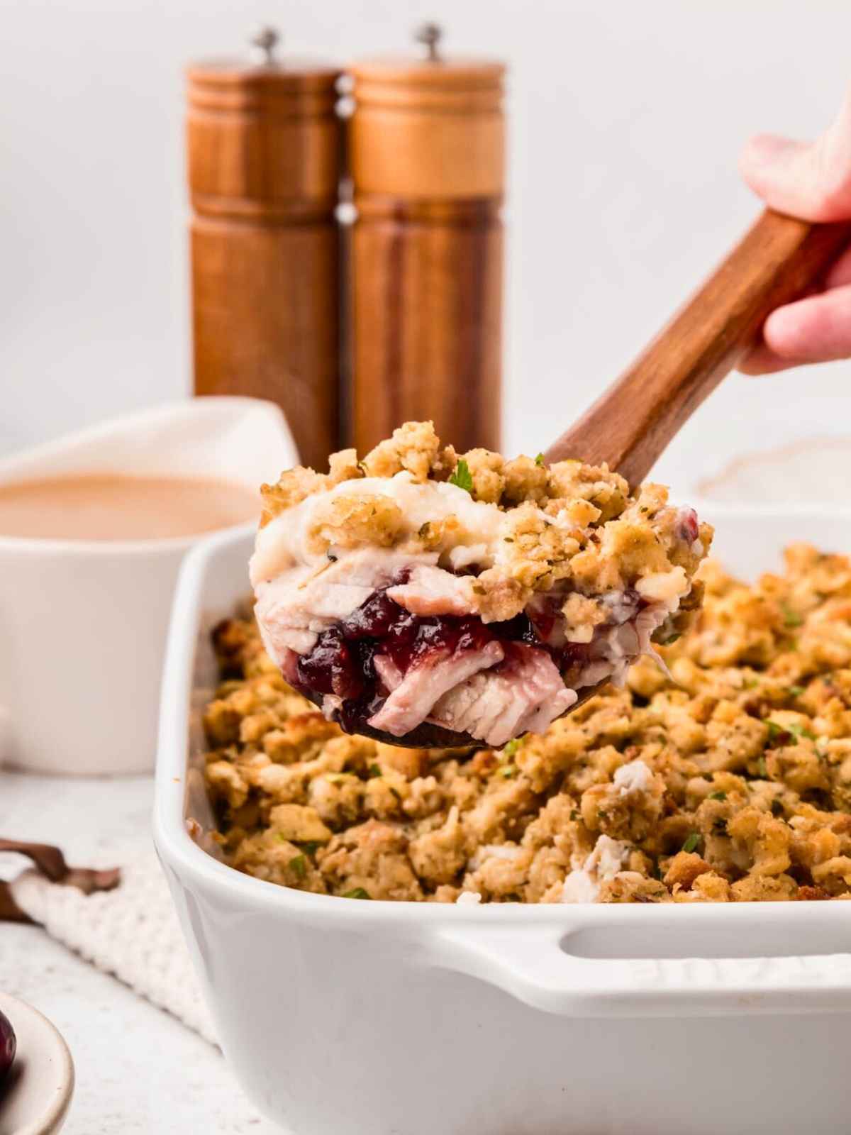 Wooden spoon lifting up a scoop of leftover turkey casserole.