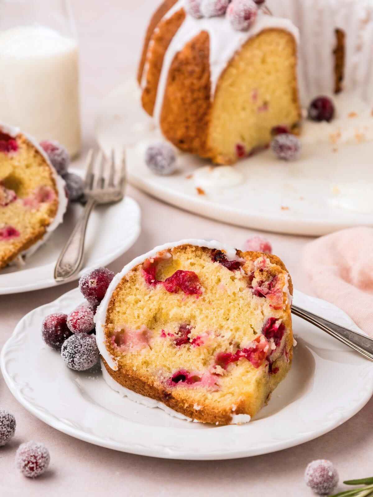 Slice of cranberry orange bundt cake on a plate with fork.