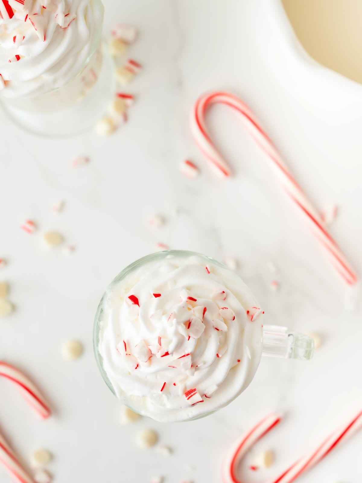 Mug of peppermint hot chocolate with candy canes on the side.