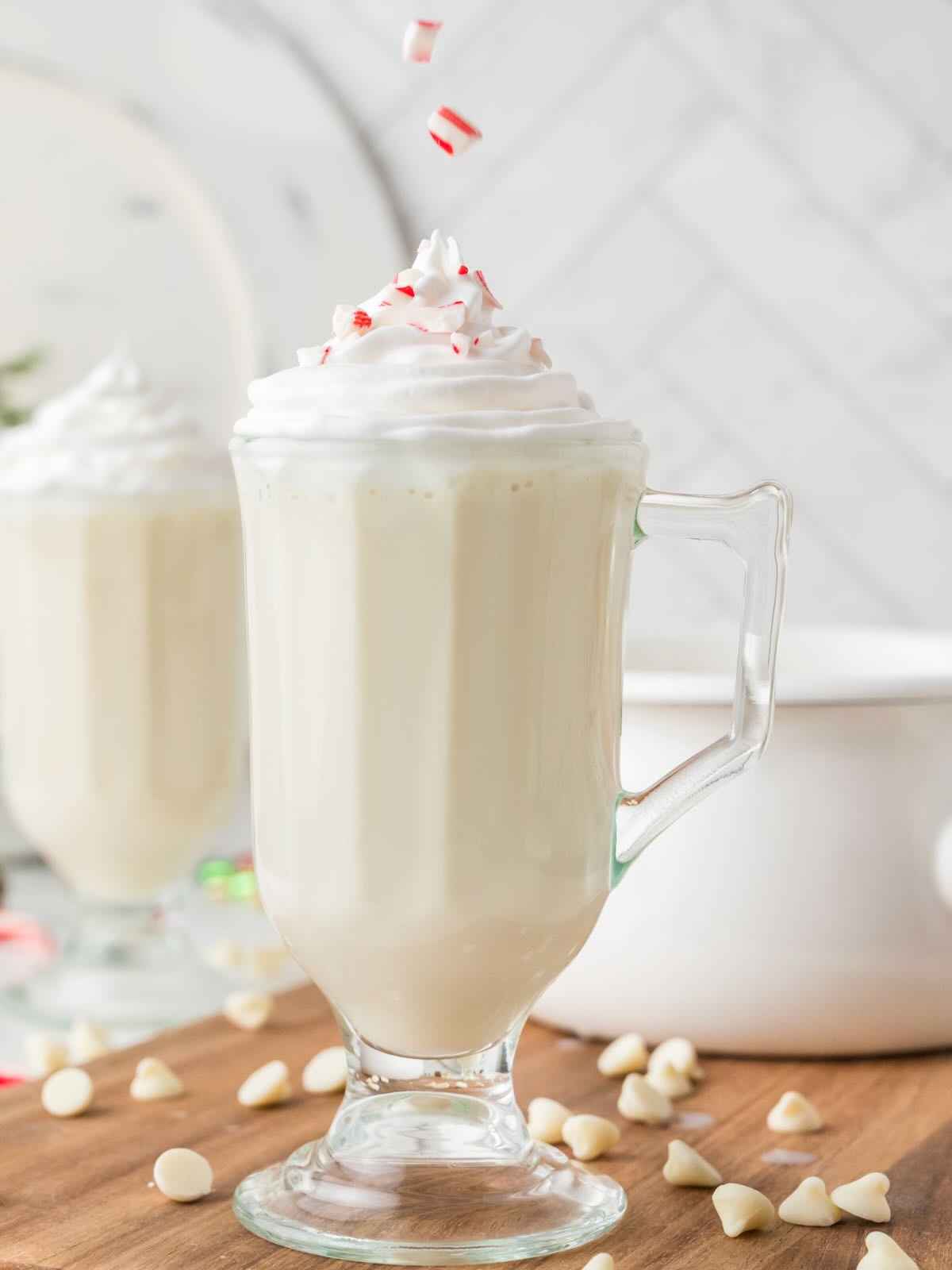 Crushed candy canes being sprinkled on top of white hot chocolate.
