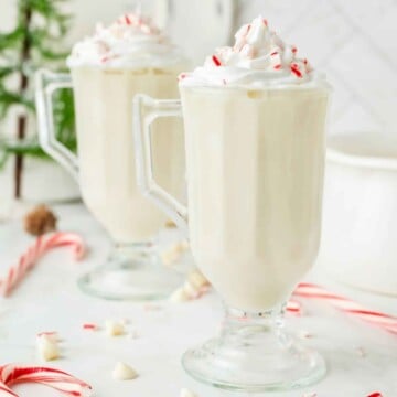 Mugs of peppermint white hot chocolate with whipped cream.