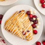 White chocolate cranberry scone on white plate.