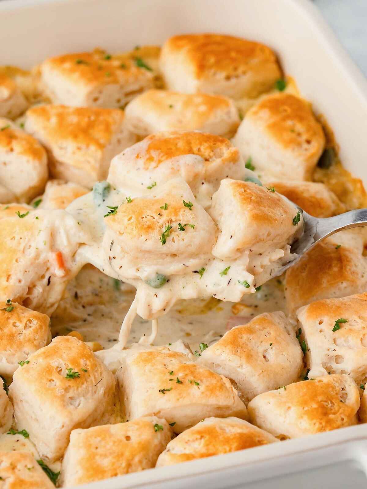 Spoon holding up chicken and biscuits.