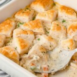 Spoon dishing out chicken biscuit casserole from baking dish.