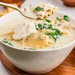 White chicken lasagna soup being held up by a spoon.
