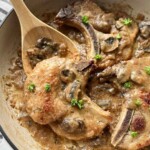 Dutch oven filled with pork chops and mushroom gravy.
