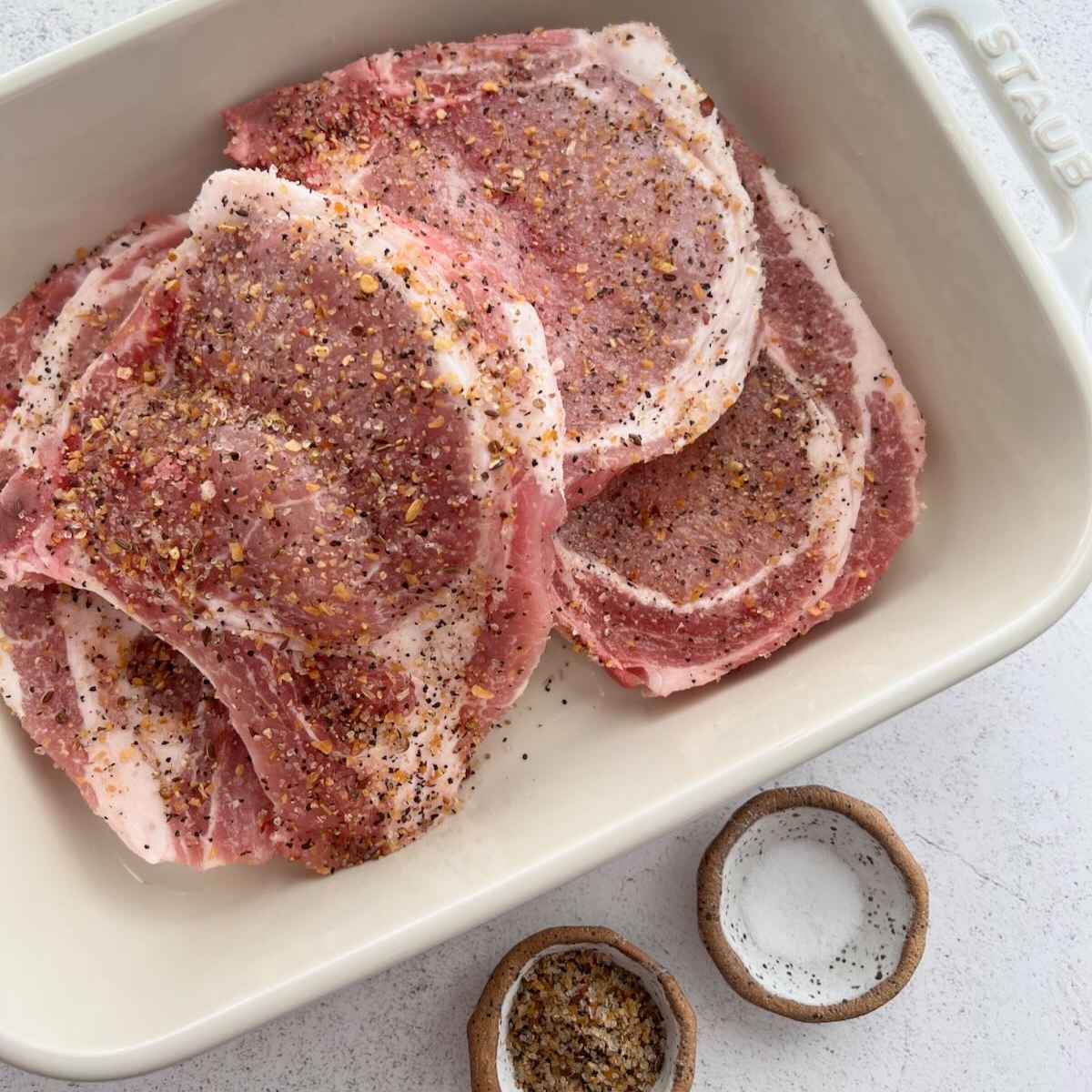 Seasoning sprinkled over pork chops.