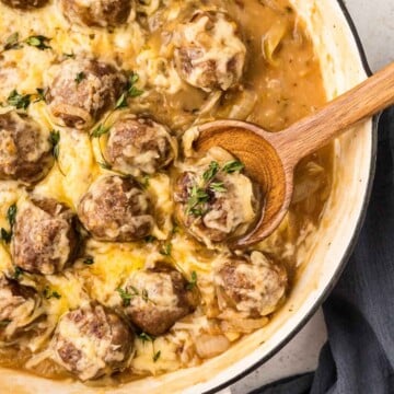 French Onion Meatballs being served with a wooden spoon.