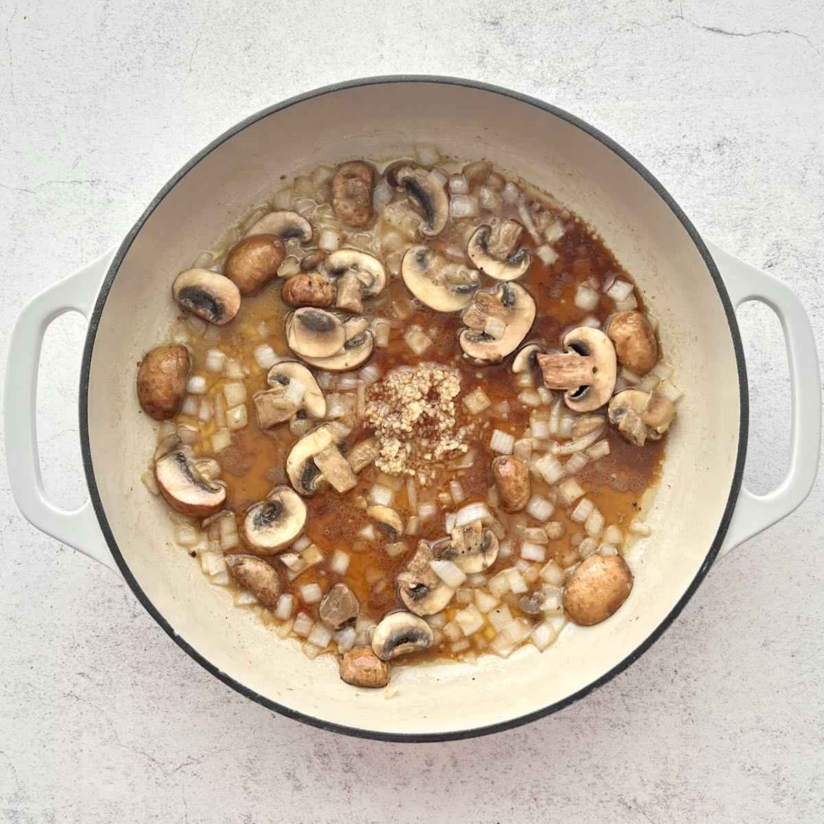 Garlic added to mushrooms and onions in dutch oven.