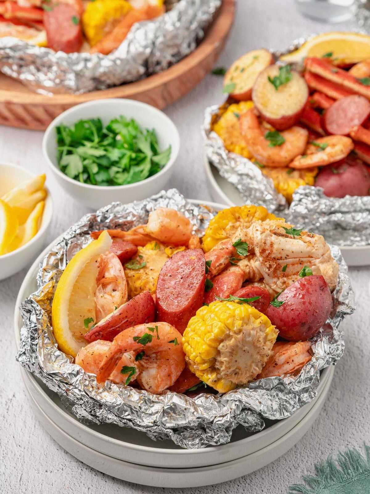 Shrimp boil in foil with shrimp, sausage, corn, and potatoes, garnished with parsley and lemon wedges.