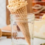 Waffle cone with a scoop of ice cream standing upright in an empty glass jar.