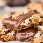 Two gooey chocolate chip cookies with melted chocolate and marshmallow filling stacked on each other.