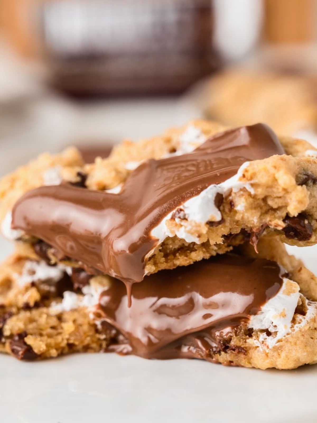 Two gooey chocolate chip cookies with melted chocolate and marshmallow filling stacked on each other.