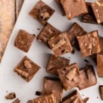 Squares of chocolate fudge with chocolate shavings on a white plate, viewed from above.