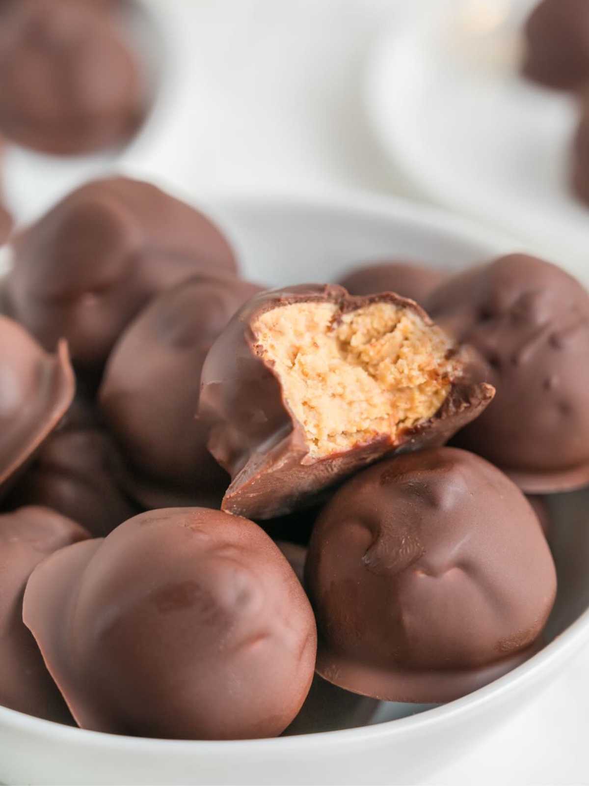 Chocolate-covered peanut butter balls, with one showing a creamy peanut butter filling inside.