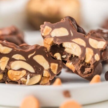 Close-up of chocolate nut clusters with visible peanuts inside, displayed on a white plate.