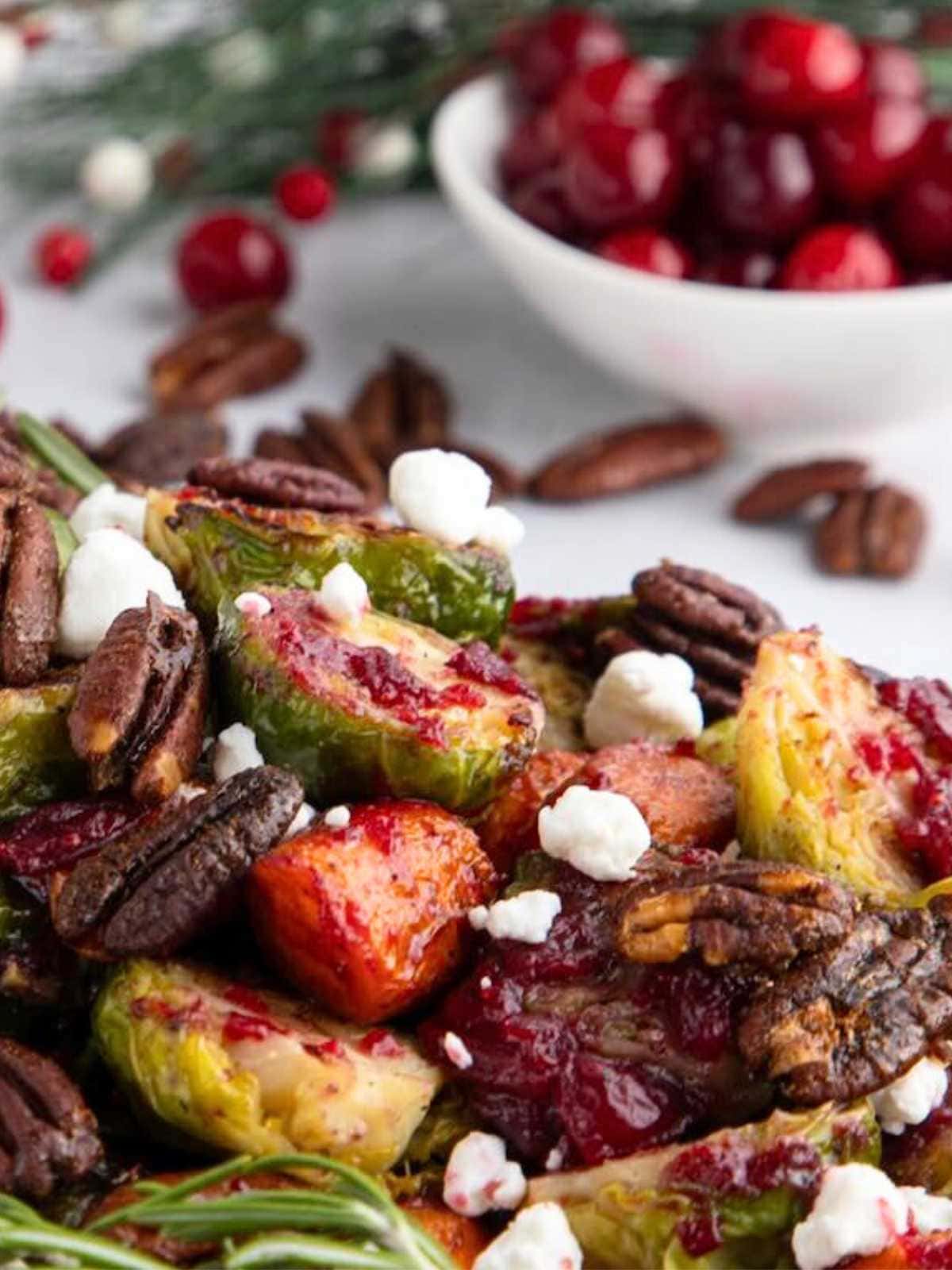 Roasted Brussels sprouts with pecans, goat cheese, and cranberries, with fresh cranberries in the background.
