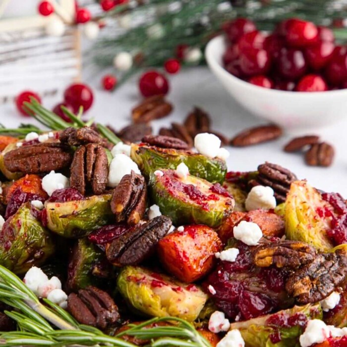 Roasted Brussels sprouts with pecans, goat cheese, and cranberry sauce, garnished with rosemary.