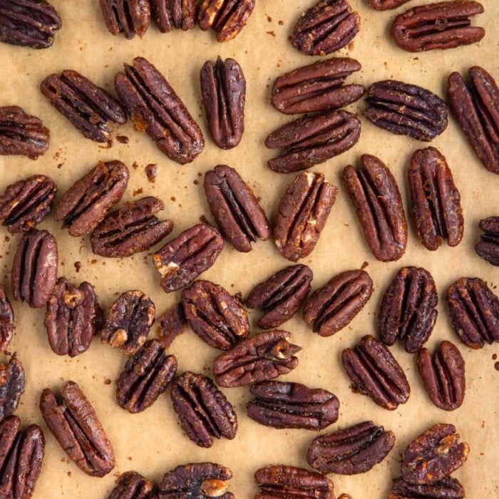 Roasted pecan halves scattered on a sheet of parchment paper.