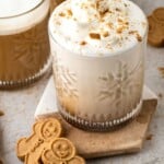 Gingerbread latte with whipped cream and cookie crumbles, served with two gingerbread cookies on the side.