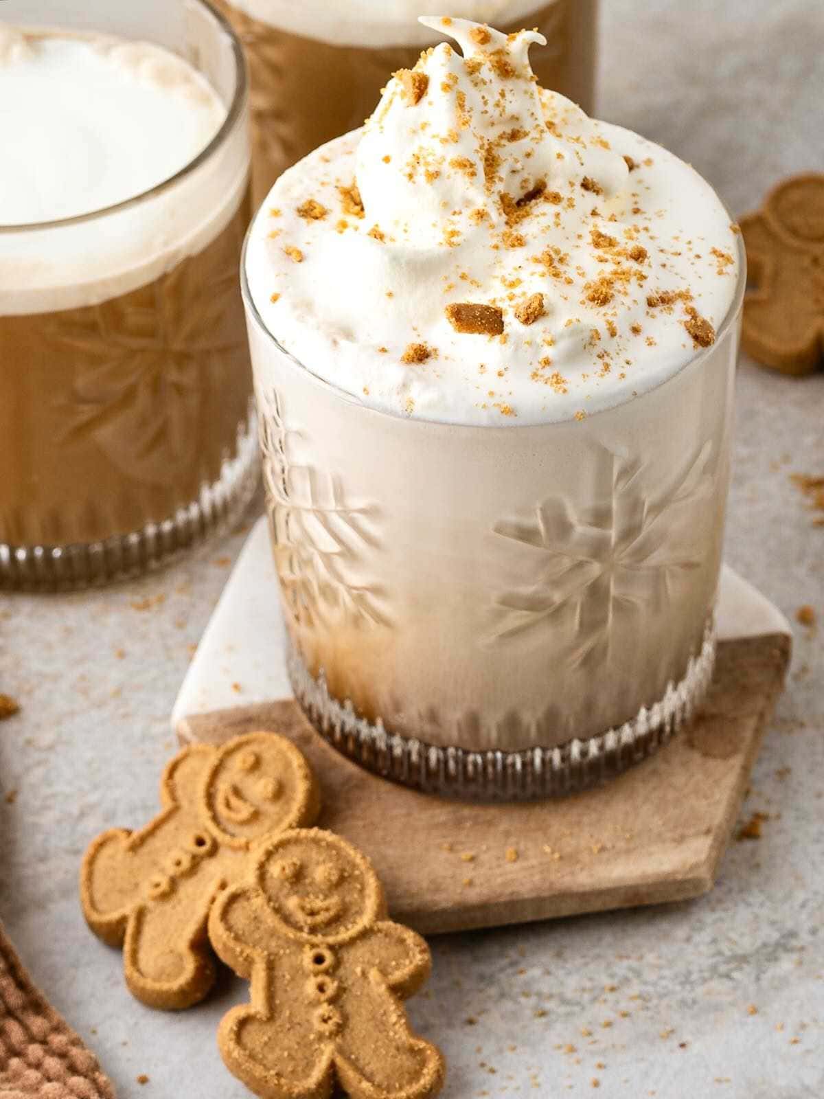 Gingerbread latte with whipped cream and cookie crumbles, served with two gingerbread cookies on the side.