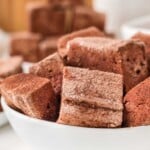 A white bowl filled with chocolate marshmallows dusted with cocoa powder.