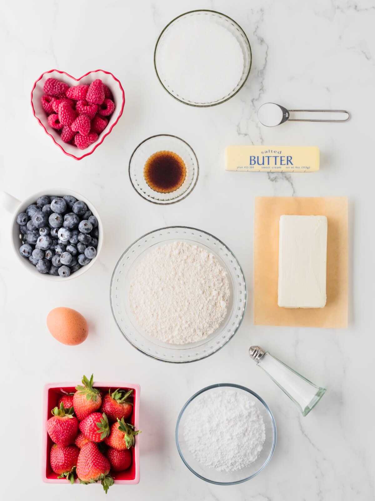 Bowl of raspberries, blueberries, strawberries, flour, sugar, butter, vanilla, egg, salt, and powdered sugar.