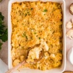 Baked cauliflower casserole with a golden breadcrumb topping, served in a white dish with a wooden spoon.