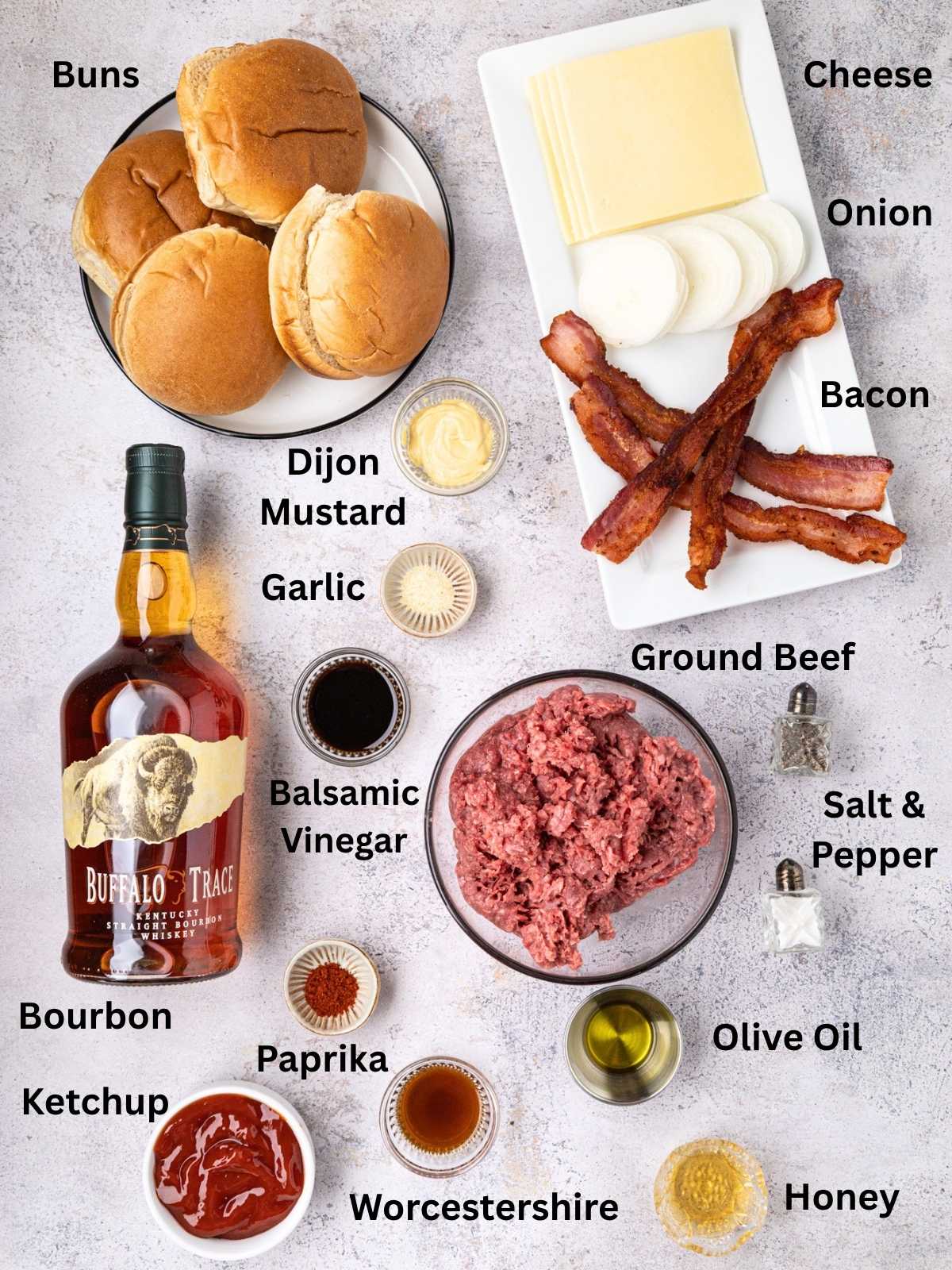 Bourbon Burger ingredients arranged on a table, including buns, cheese, onion, bacon, ground beef, condiments, and seasonings.