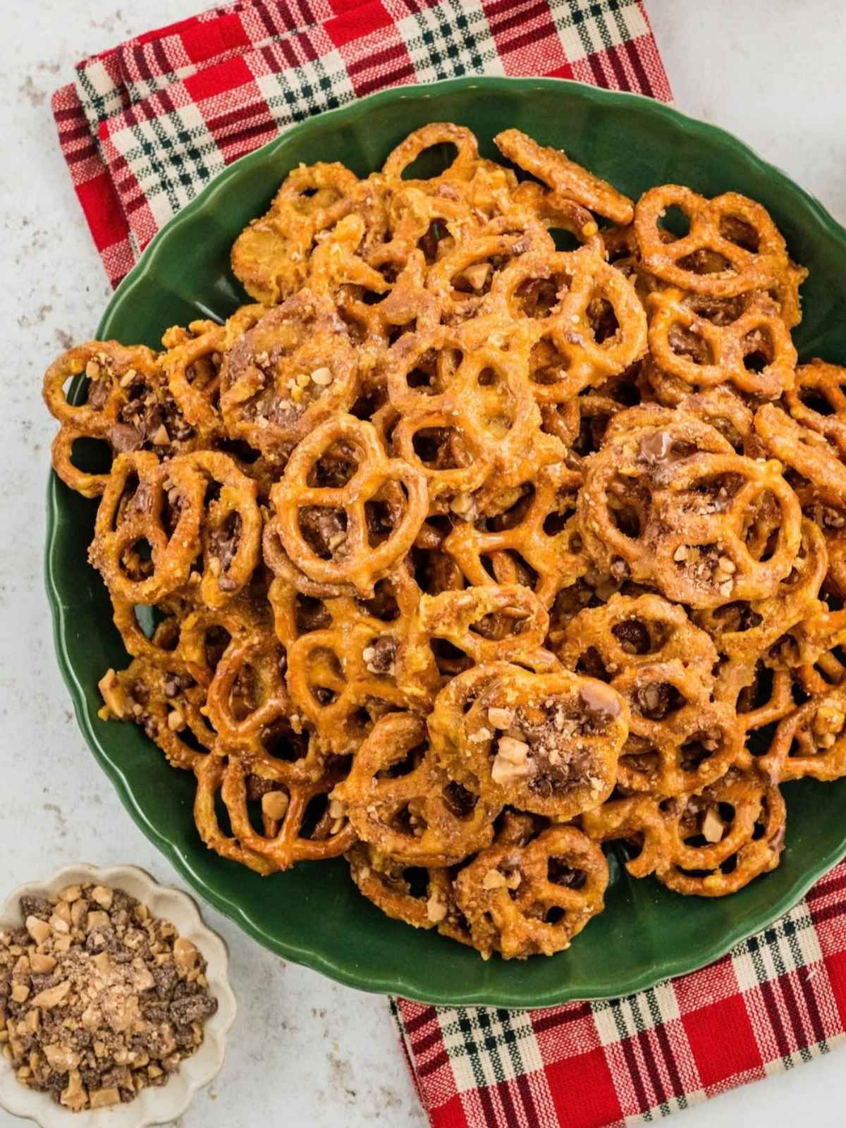 Green plate piled with bite-sized pretzels coated in a brown cinnamon-sugar mixture.