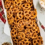 A wooden crate filled with caramel-coated pretzels topped with chopped toffee.