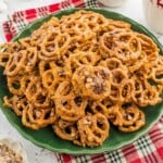 A pile of glazed, toffee-topped pretzels on a green plate.