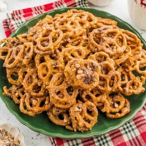 A pile of glazed, toffee-topped pretzels on a green plate.